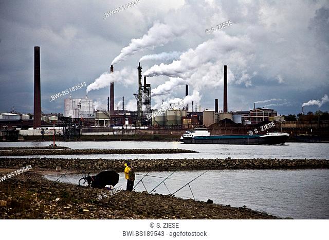 two anglers at Rhine in front of industrial plants, Germany, North Rhine-Westphalia, Ruhr Area, Duisburg