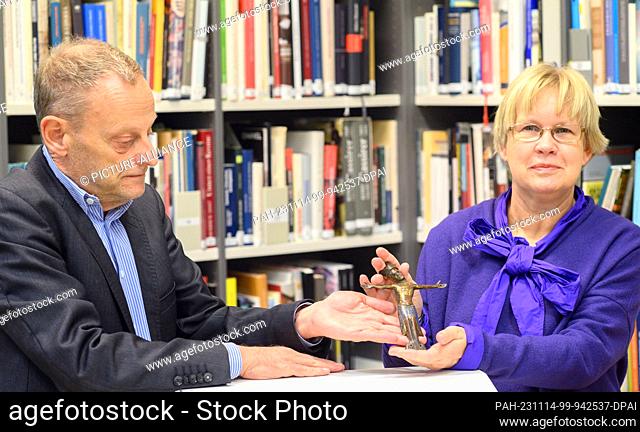 14 November 2023, Saxony-Anhalt, Magdeburg: Gilbert Lupfer (l), Director of the German Lost Art Foundation, hands over a bronze crucifix from the 13th century...