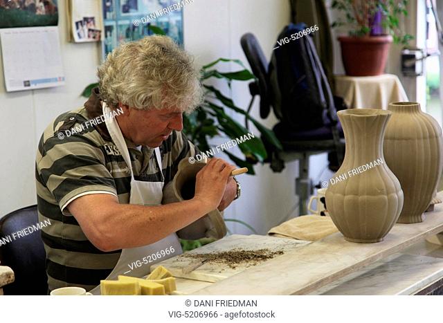 An artisan carefully shapes a vase at the Royal Delft factory in Delft, Netherlands, Europe. Delftware, the distinctive Dutch blue and white pottery is produced...