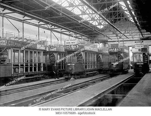 Interior view of a tramshed at Lytham St Annes, Lancashire, showing various trams with advertising material: Jacob's Cream Crackers, Colman's Mustard