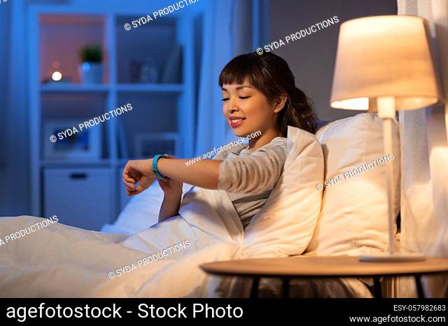 asian woman with health tracker in bed at night