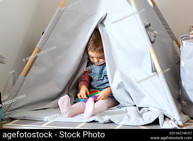 girl playing with fidget toy in teepee at home
