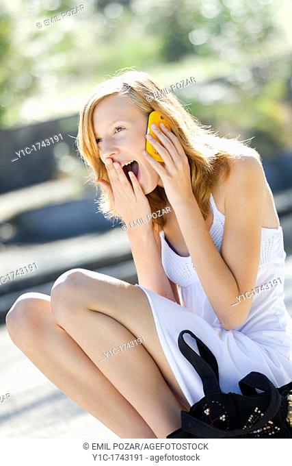 Laughing young woman uses cellphone