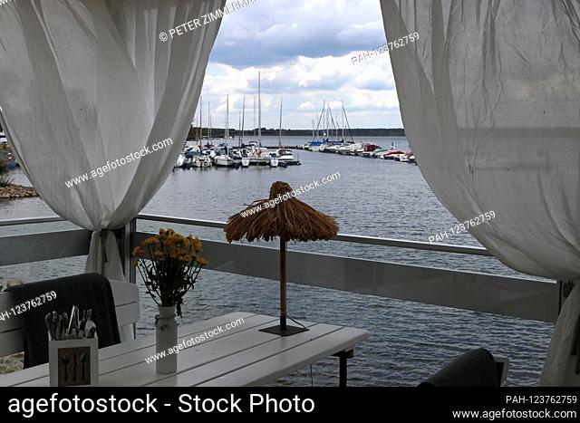 View from a restaurant below the lighthouse at Geierswalder See on the border of Brandenburg and Saxony onto a jetty with sailing boats on August 14th, 2019