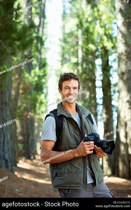 Smiling man with digital camera in woods