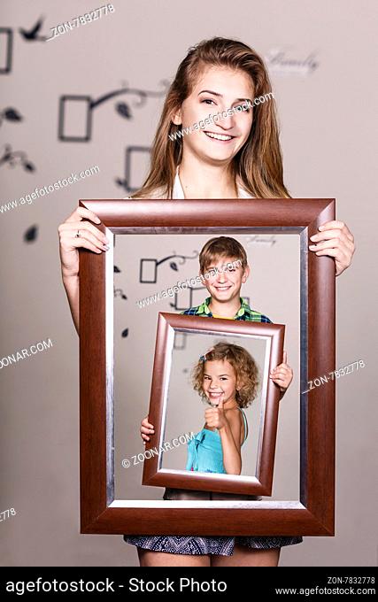 Happy adult sister holding portrait with her family each is located inside their own frame