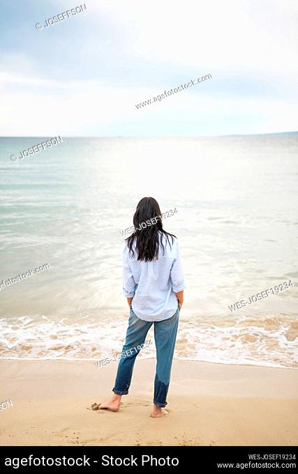 Woman spending leisure time standing near shore at beach