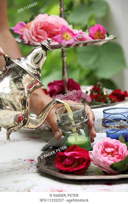 A rose-flavoured sleeping draught being poured into a tea glass decorated with silver