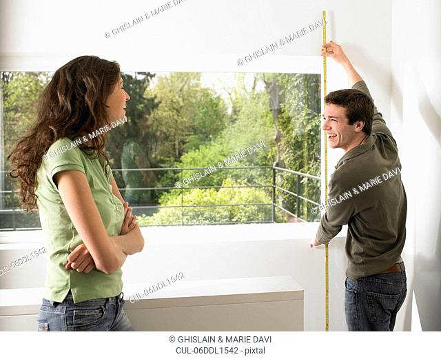 Couple taking measurement of their home