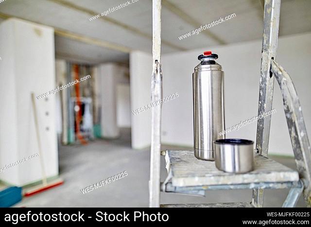 Thermos flask and ladder on construction site
