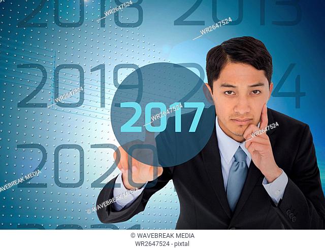 Thoughtful business man in digitally generated background touching 2017