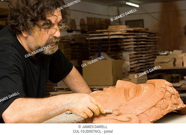 Man sculpting face in clay