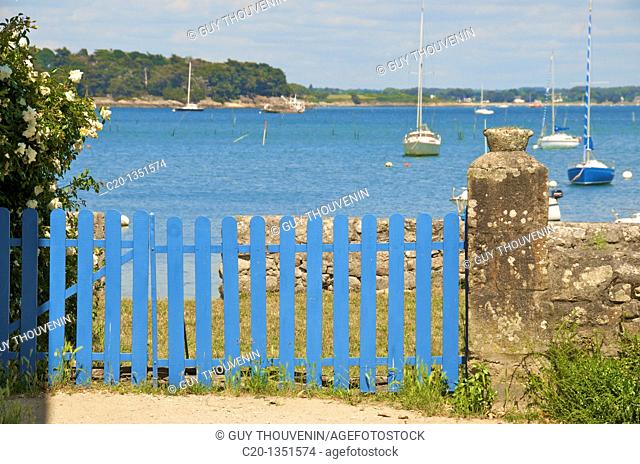 Garden with flowers and blue gate in front of the sea at Locmariaquer Morbihan Brittany 56 France
