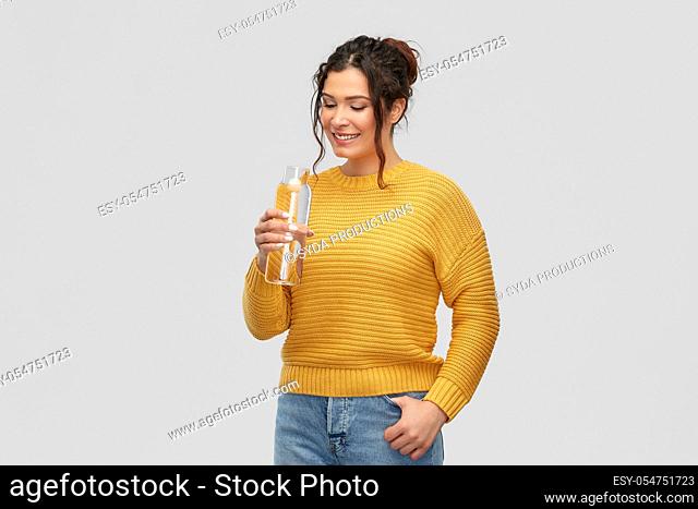 smiling young woman with water in glass bottle