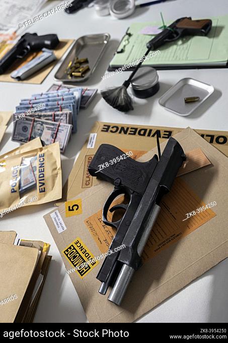 Money and weapons in crime lab for investigation, conceptual image