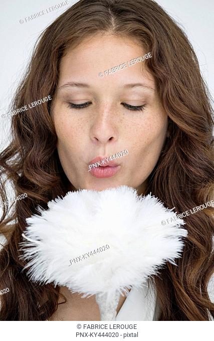 Woman blowing on a feather duster