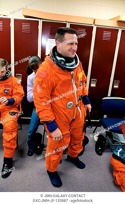 Astronaut Christopher J. (Gus) Loria, STS-113 pilot, assisted by a technician, dons a training version of the full-pressure launch and entry suit prior to the...