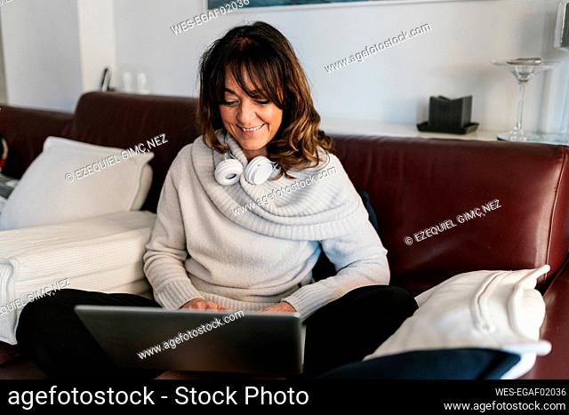 Smiling mature woman using laptop while sitting at home