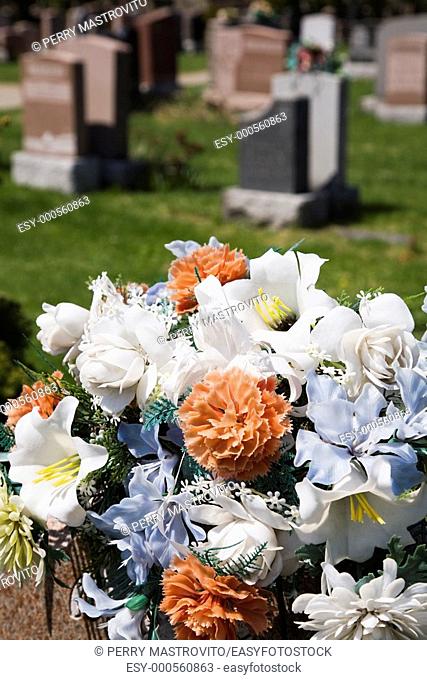 Close-up of a bouquet of artificial flowers atop a headstone in a cemetery, Laval, Quebec, Canada