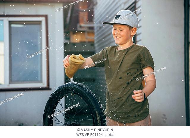 Happy boy cleaning bmx bike on yard