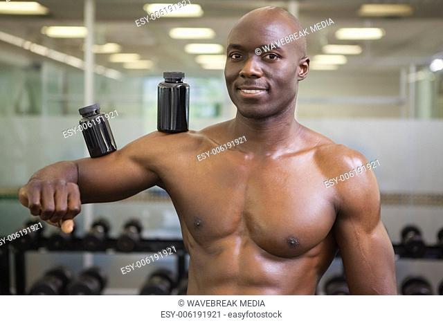 Body builder holding bottles with supplements on biceps