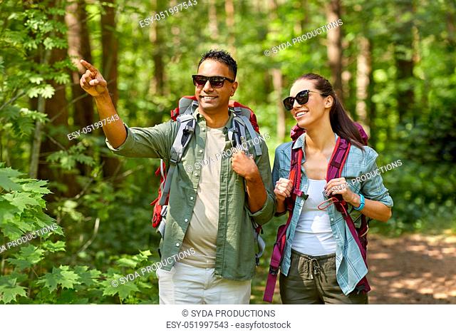 mixed race couple with backpacks hiking in forest