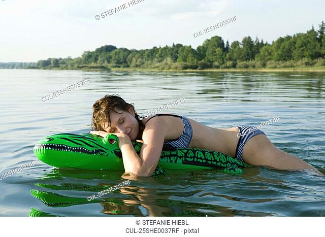 Girl laying on air crocodile in water
