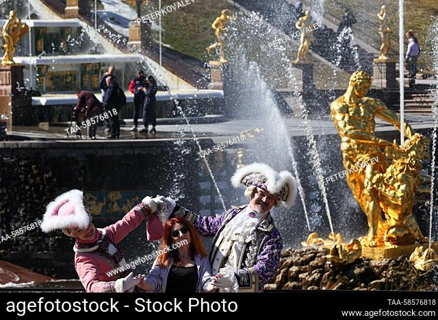 RUSSIA, ST PETERSBURG - APRIL 22, 2023: Entertainers pose with a woman in front of the Samson Tearing Apart the Lion's Jaws fountain in the Lower Park during...