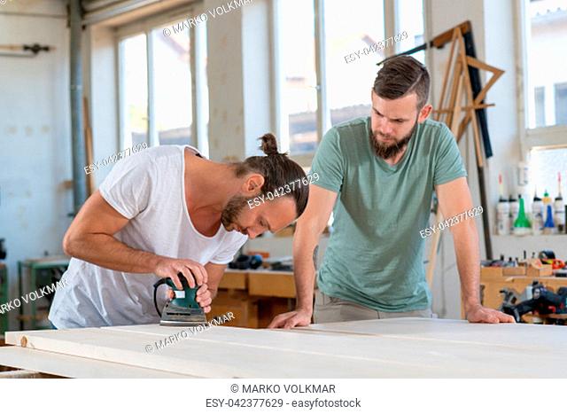 two men in workwear in a carpenter's workshop