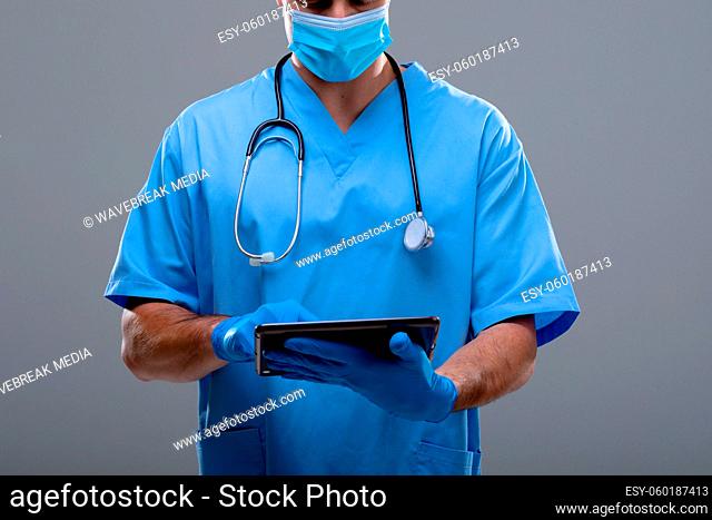 Caucasian male doctor wearing face mask using tablet