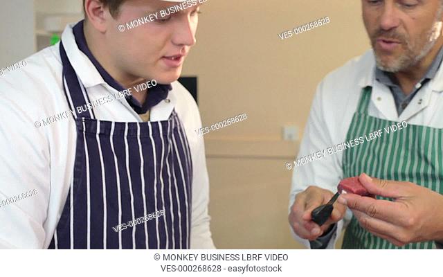Butcher explaining to apprentice the correct way to prepare meat.Shot on Sony FS700 in PAL format at a frame rate of 25fps