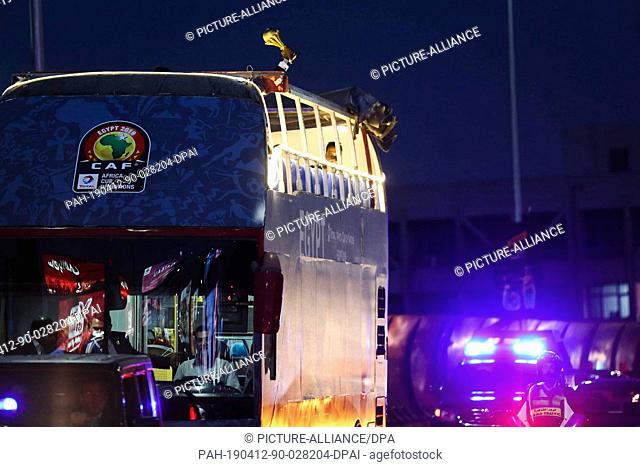12 April 2019, Egypt, Cairo: Retired Cameroonian footballer Rigobert Song holds the Africa Cup of Nations (AFCON) trophy on top of an open top bus during a tour...