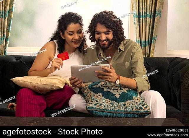 Young couple shopping online through tablet using credit card