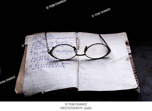 Germany, Bavaria, Josefsthal, opened order book and glasses in front of black background