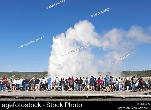 Rear view of tourists looking at geyser in Yellowstone Park