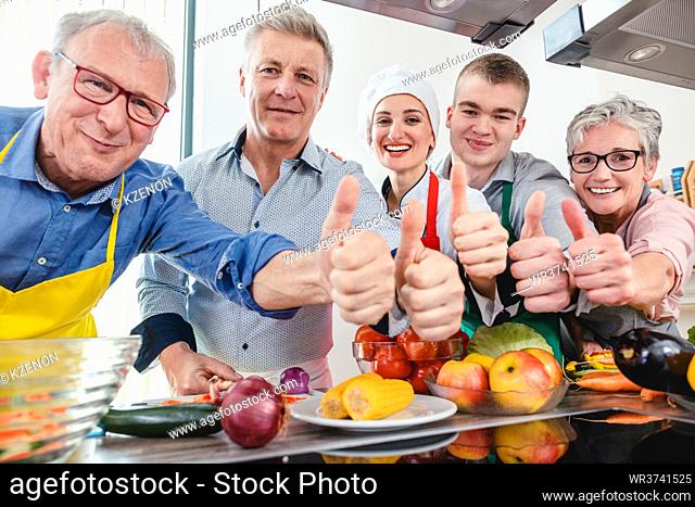 Trainees and their nutritionist chef in a training kitchen showing thumbs