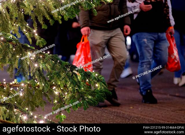 PRODUCTION - 15 December 2023, North Rhine-Westphalia, Cologne: Two men carrying shopping bags in the Schildergasse pedestrian zone