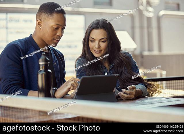 Portrait of young people working on a tablet at an outdoor cafe