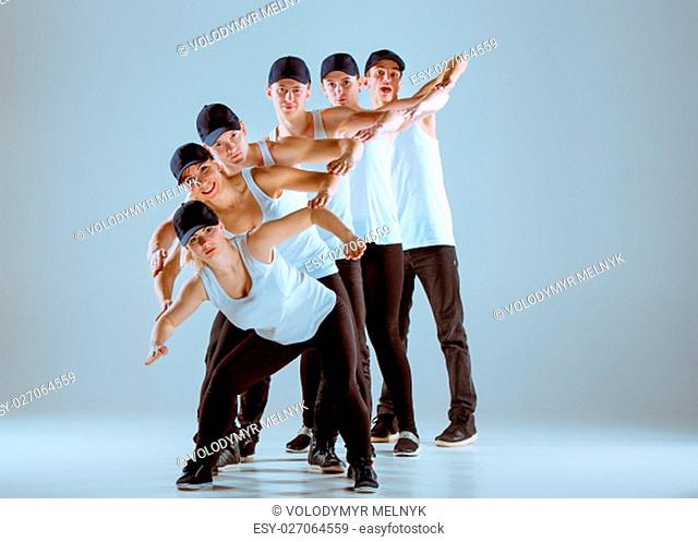 Group of men and women dancing fitness or hip hop choreography in gray studio background