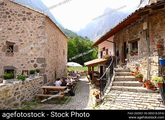07 August 2020, Spain, Bulnes: A restaurant and houses in front of the limestone cliffs in the National Park Picos de Europa
