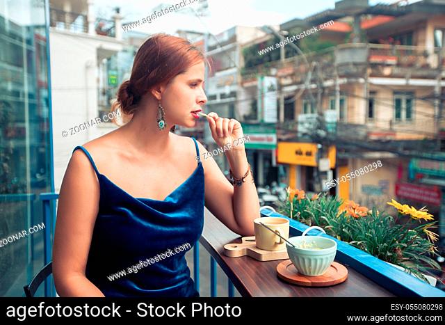 Beautiful woman enjoying tea and dessert on cafe terrace in Dalat, Vietnam
