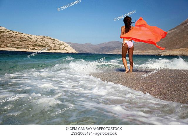 Woman in bikini walking towards the waves at the beach, Amorgos, Cyclades Islands, Greek Islands, Greece, Europe
