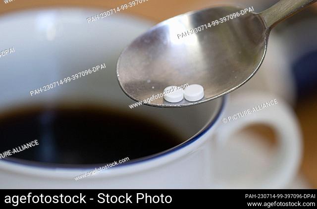 PRODUCTION - 12 July 2023, Saxony, Leipzig: A spoon with two sweetener tablets is seen above a cup of coffee. A sweetener commonly used in soft drinks