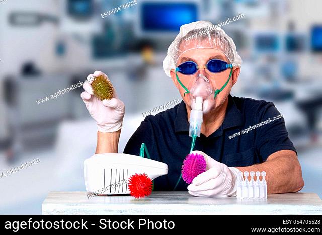 Coronavirus treatment concept. Man at table with nebulizer mask, safety goggles and medical hair hood and gloves shows abstract models of virus covid-19 and...
