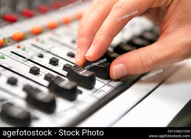 Male hand on control Fader on console. Sound recording studio mixing desk with engineer or music producer