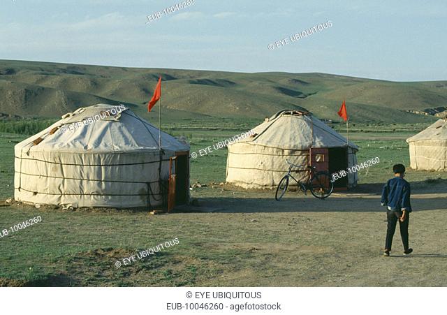 Man walking past two yurts