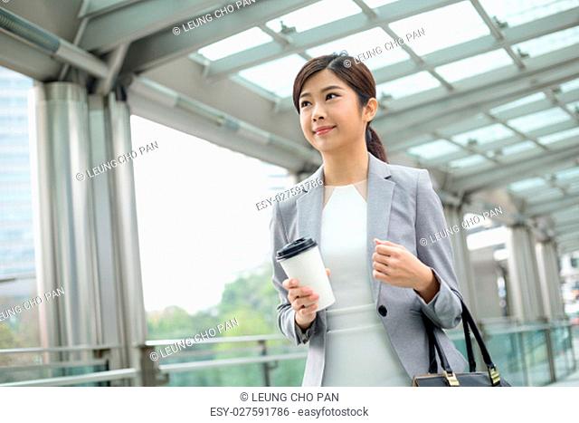 Asian Businesswoman holding a coffee and walking outdoor