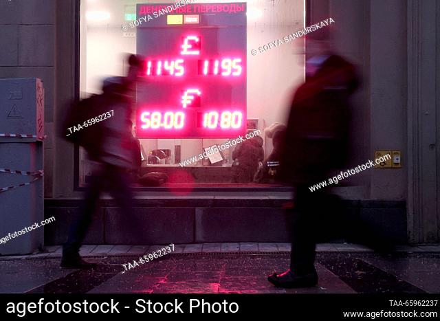 RUSSIA, MOSCOW - DECEMBER 21, 2023: People walk past an information board showing foreign currency exchange rates. The Bank of Russia has set the US dollar rate...