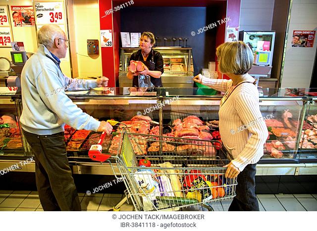 Senior couple shopping at the meat counter in the supermarket, Germany