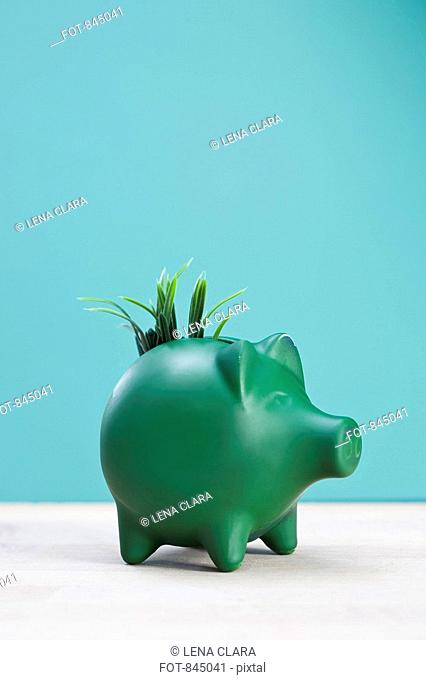 A green piggy bank with grass growing from it